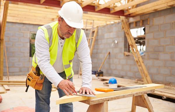 Man in hi-vis vest and hard hat working on a building site.