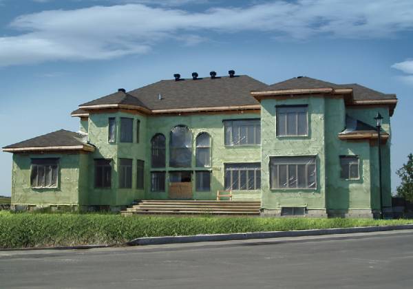 Large home under construction covered in green spray foam. 